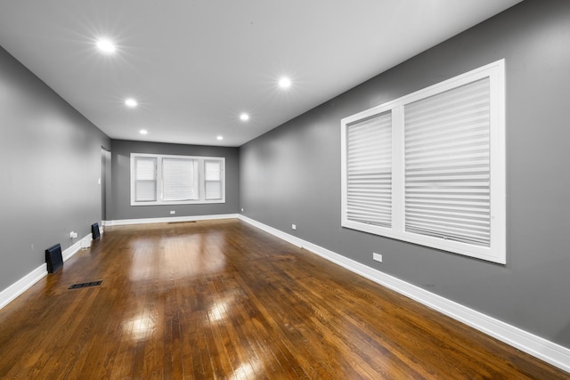 spare room featuring hardwood / wood-style floors, recessed lighting, visible vents, and baseboards