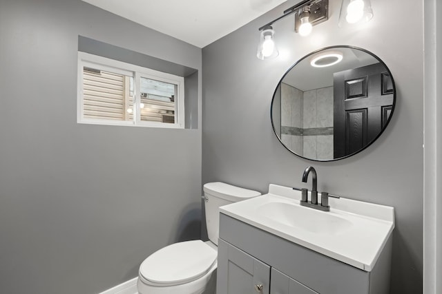 bathroom with toilet, vanity, and baseboards