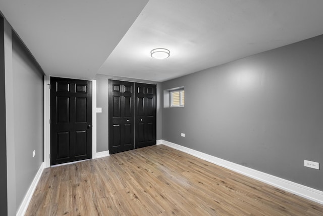 unfurnished bedroom with light wood-type flooring, baseboards, and a closet