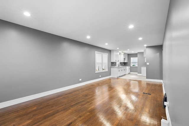 unfurnished living room featuring light wood finished floors, recessed lighting, visible vents, and baseboards