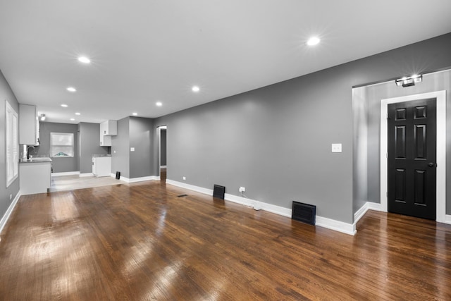 unfurnished living room with dark wood-style floors, visible vents, and recessed lighting