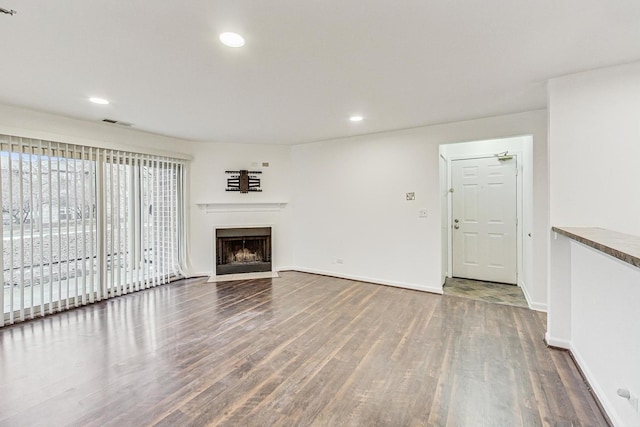 unfurnished living room featuring recessed lighting, a fireplace, baseboards, and wood finished floors