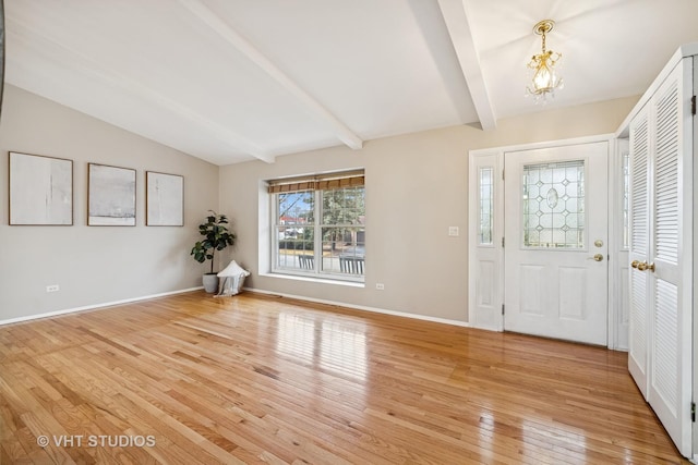 entrance foyer featuring vaulted ceiling with beams, light wood-type flooring, baseboards, and an inviting chandelier