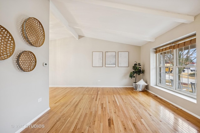 empty room featuring baseboards, vaulted ceiling with beams, and hardwood / wood-style floors