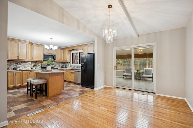 kitchen featuring a chandelier, appliances with stainless steel finishes, backsplash, and a center island