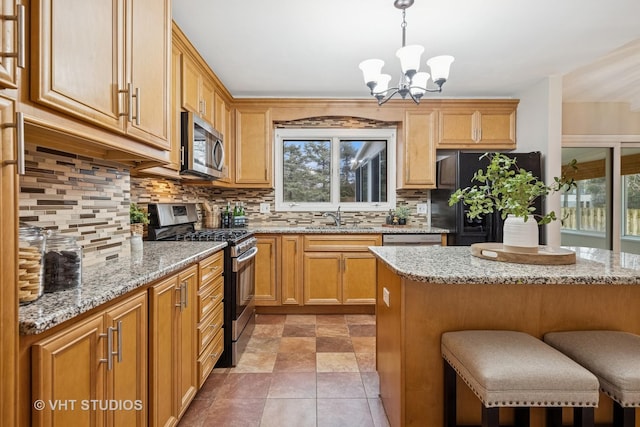 kitchen with a breakfast bar, a sink, appliances with stainless steel finishes, a wealth of natural light, and decorative backsplash