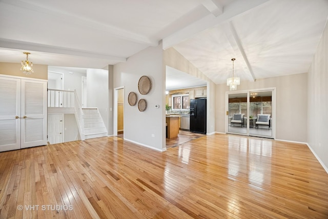 unfurnished living room featuring stairs, light wood finished floors, vaulted ceiling with beams, and a notable chandelier