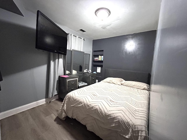 bedroom with wood finished floors, visible vents, and baseboards