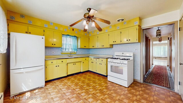 1222 Austin St, Evanston, IL 60202 - kitchen with white appliances, a ceiling fan, backsplash, yellow cabinets, and a baseboard radiator