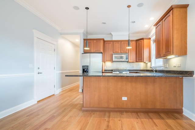 kitchen with a peninsula, dark stone countertops, brown cabinets, and stainless steel appliances