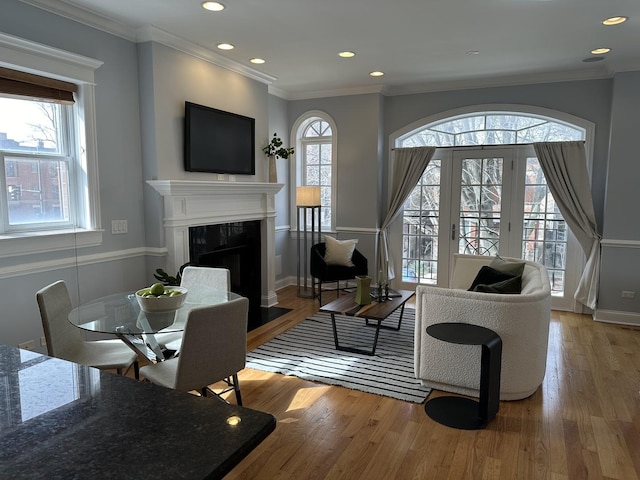 living area with wood finished floors, a fireplace, and crown molding