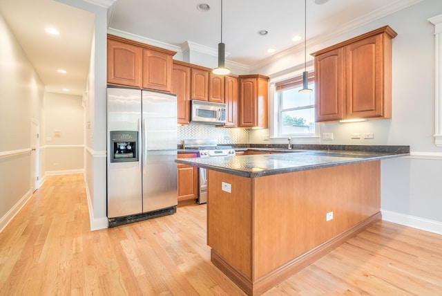 kitchen featuring brown cabinetry, light wood finished floors, a peninsula, ornamental molding, and stainless steel appliances