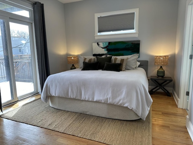 bedroom with access to outside, wood finished floors, and baseboards