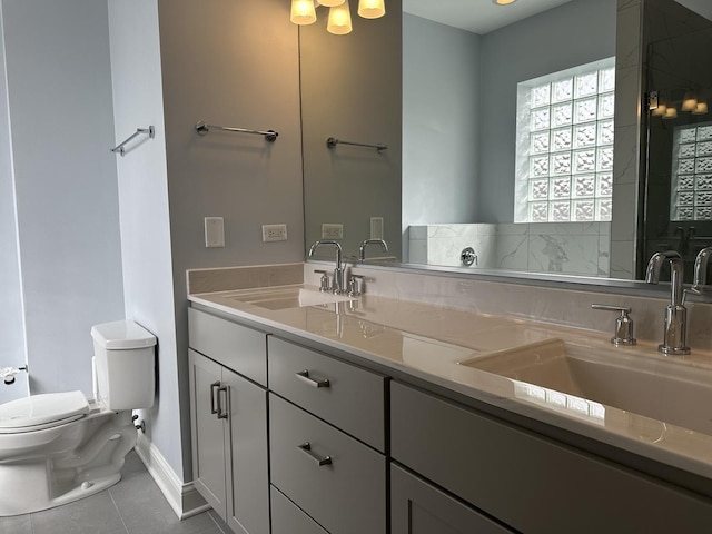 bathroom with a sink, toilet, double vanity, and tile patterned flooring