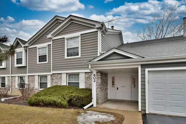 view of property featuring an attached garage, stone siding, and a shingled roof