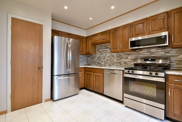 kitchen with appliances with stainless steel finishes, backsplash, and brown cabinets