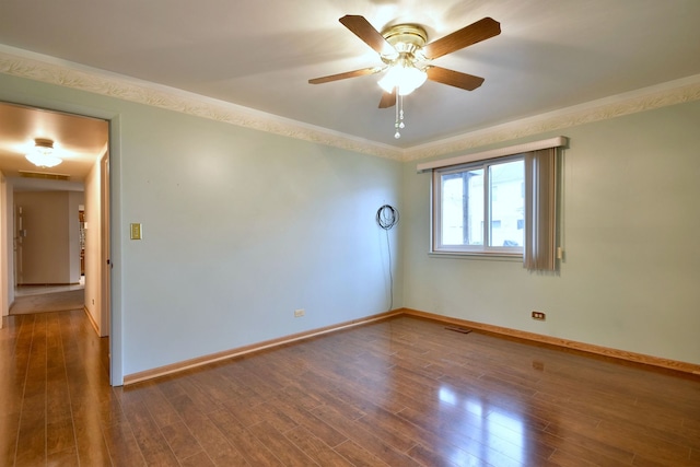 empty room with ornamental molding, visible vents, baseboards, and wood finished floors