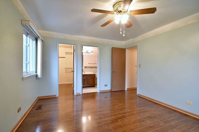 unfurnished bedroom with baseboards, visible vents, wood finished floors, a walk in closet, and a sink