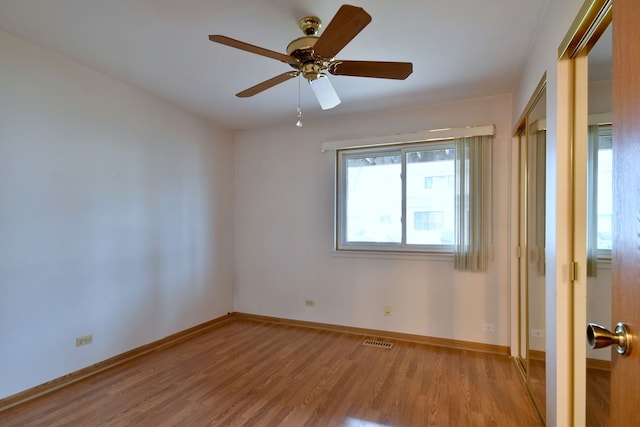 unfurnished bedroom with a ceiling fan, visible vents, baseboards, and wood finished floors