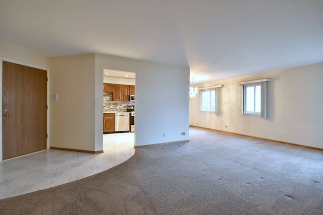 unfurnished living room featuring light carpet, an inviting chandelier, baseboards, and light tile patterned flooring