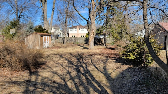 view of yard featuring an outdoor structure, fence, and a shed