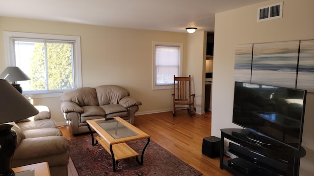 living area with wood finished floors, visible vents, and baseboards