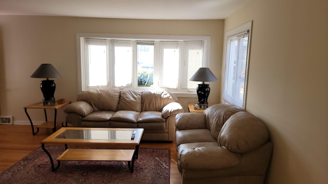 living room with visible vents, baseboards, and wood finished floors