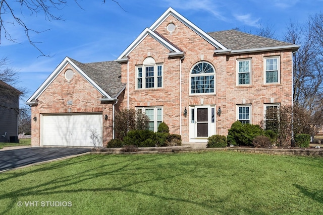 colonial inspired home featuring brick siding, a front lawn, aphalt driveway, roof with shingles, and an attached garage