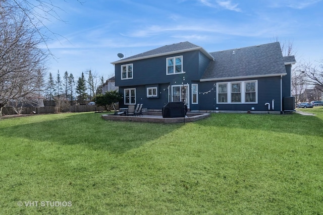 rear view of property featuring a patio area, a yard, fence, and roof with shingles