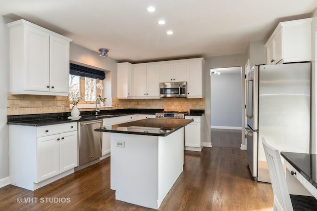 kitchen featuring a sink, backsplash, appliances with stainless steel finishes, white cabinets, and dark wood-style flooring