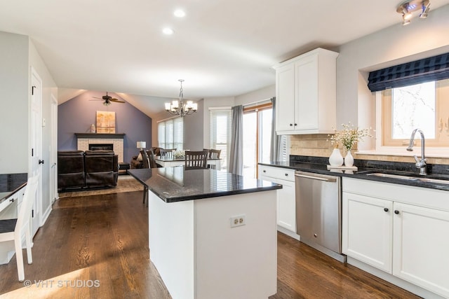 kitchen featuring a sink, a center island, a fireplace, dishwasher, and dark wood-style flooring