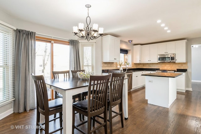 dining space featuring baseboards, recessed lighting, dark wood-style flooring, and a chandelier