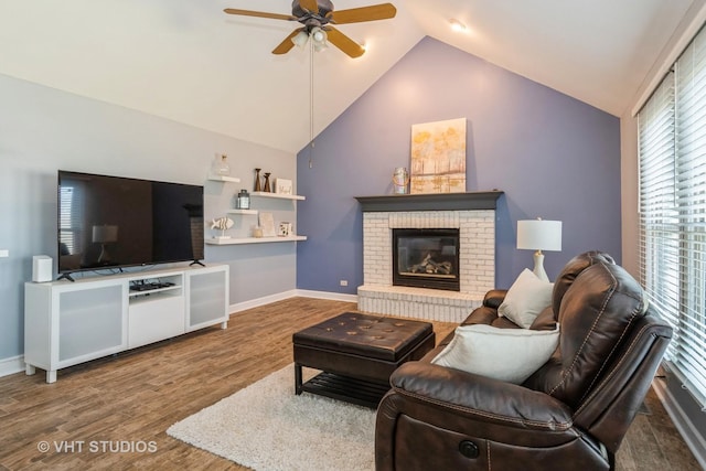 living room featuring ceiling fan, baseboards, a brick fireplace, and wood finished floors