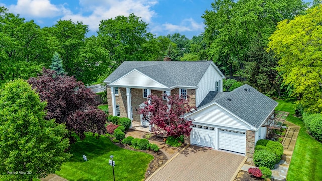 greek revival inspired property with decorative driveway, brick siding, a chimney, a shingled roof, and an attached garage