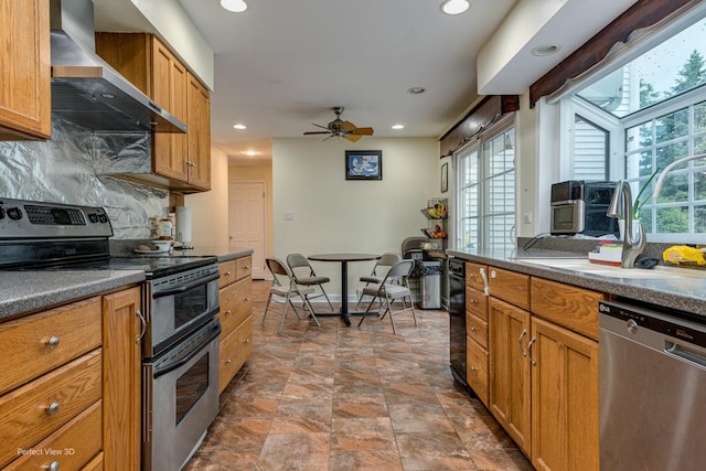 kitchen with stainless steel appliances, dark countertops, plenty of natural light, and wall chimney range hood