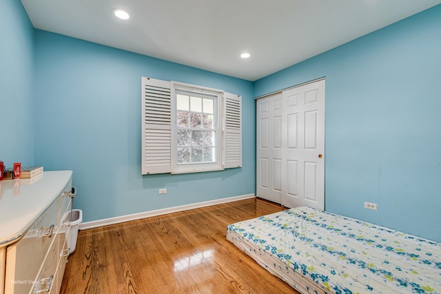 bedroom featuring a closet, baseboards, wood finished floors, and recessed lighting