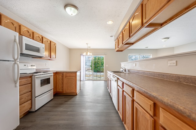 kitchen with dark wood-style floors, decorative light fixtures, brown cabinets, a sink, and white appliances