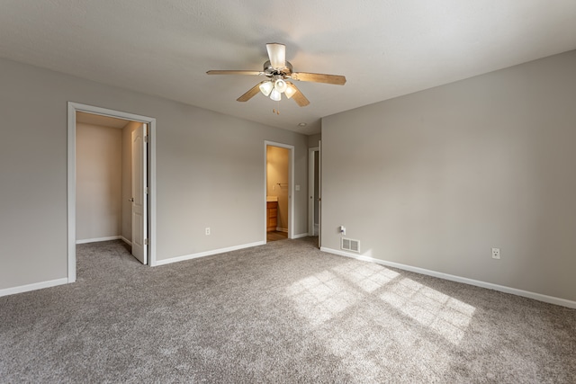 unfurnished bedroom with light colored carpet, visible vents, a spacious closet, ceiling fan, and baseboards