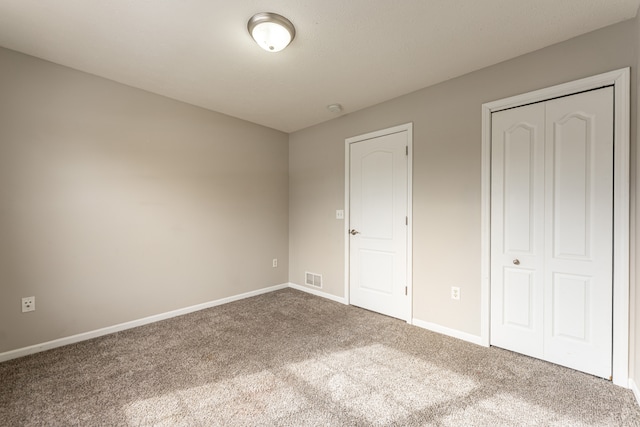 unfurnished bedroom with carpet, a closet, visible vents, and baseboards