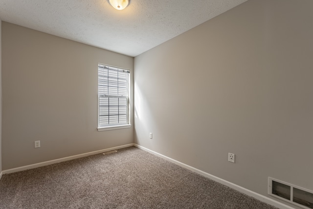 spare room with a textured ceiling, carpet flooring, visible vents, and baseboards