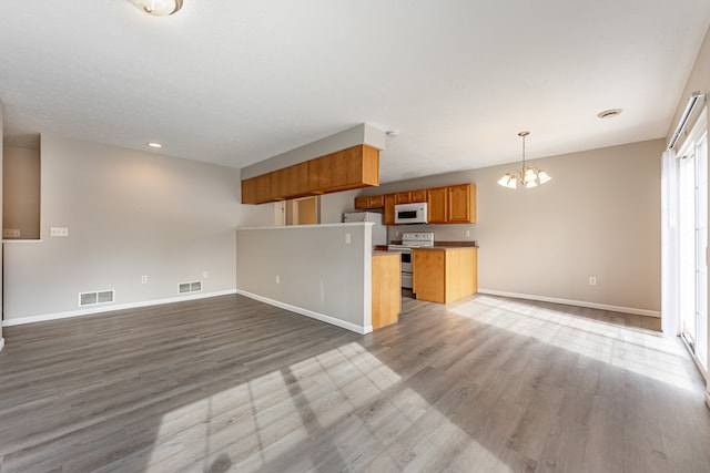 kitchen featuring visible vents, white microwave, open floor plan, freestanding refrigerator, and pendant lighting