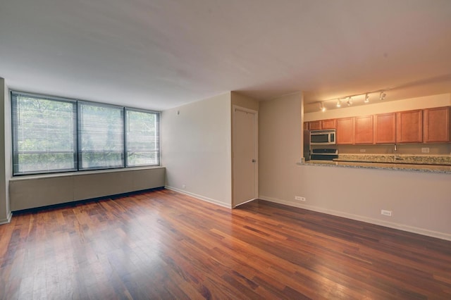 unfurnished living room featuring dark wood-style floors, a sink, and baseboards