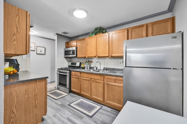 kitchen with dark countertops, crown molding, stainless steel appliances, and a sink