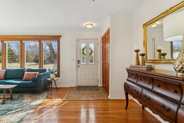 foyer featuring crown molding, light wood-style flooring, and baseboards