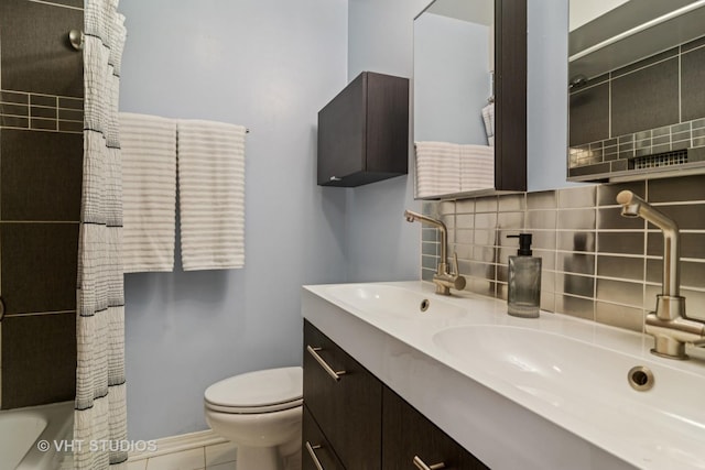 bathroom featuring a sink, decorative backsplash, toilet, and double vanity