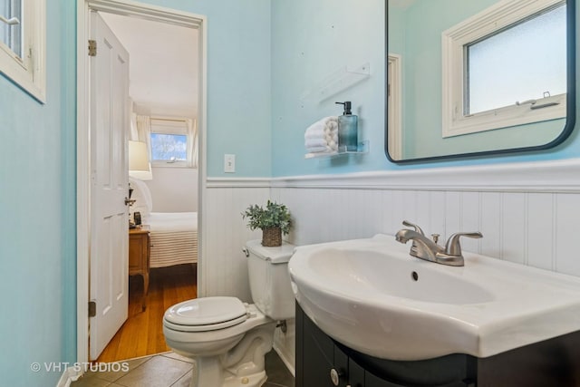 bathroom featuring vanity, tile patterned flooring, ensuite bathroom, wainscoting, and toilet