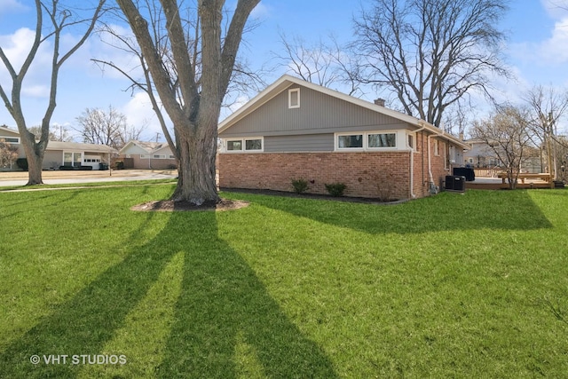 view of side of home featuring cooling unit, a lawn, a chimney, and brick siding