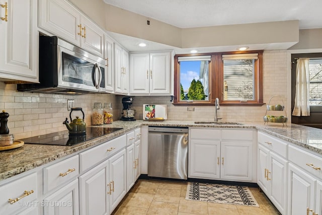 kitchen featuring a sink, backsplash, stainless steel appliances, white cabinets, and light stone countertops