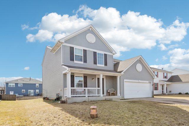 traditional home with a front lawn, fence, a porch, concrete driveway, and a garage