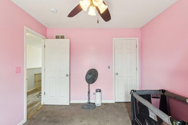 carpeted bedroom with visible vents, baseboards, and a ceiling fan